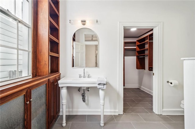 bathroom featuring tile patterned flooring, a spacious closet, toilet, and baseboards