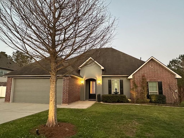 ranch-style house with stucco siding, driveway, a front yard, an attached garage, and brick siding