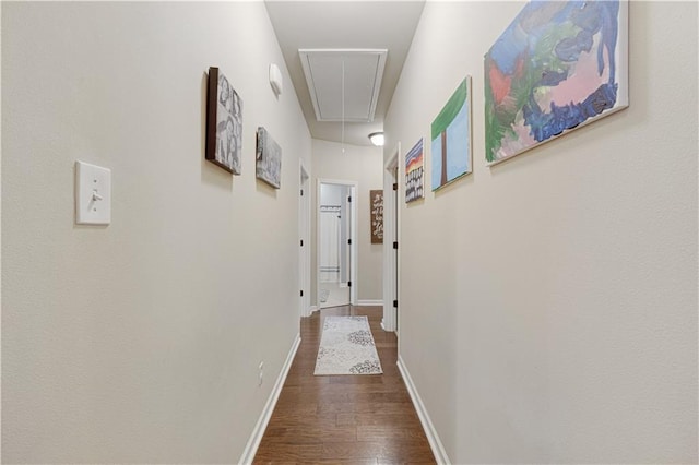 hallway with baseboards, attic access, and dark wood finished floors