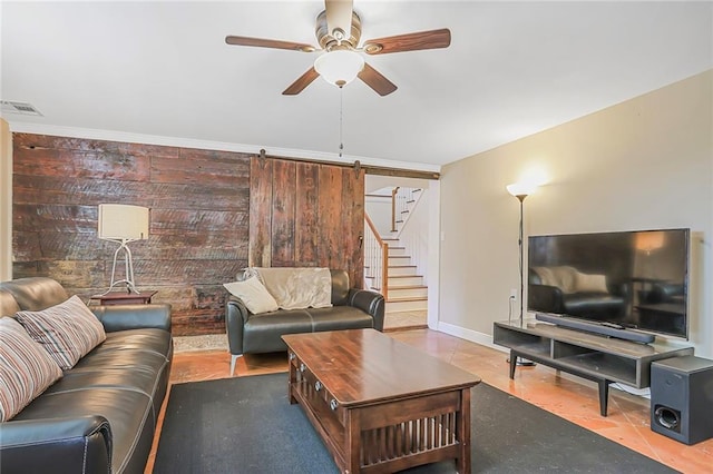 living room with visible vents, a ceiling fan, a barn door, baseboards, and stairs