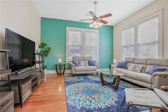 living area with light wood-type flooring, baseboards, visible vents, and ceiling fan