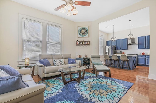 living room with light wood-style floors and a ceiling fan