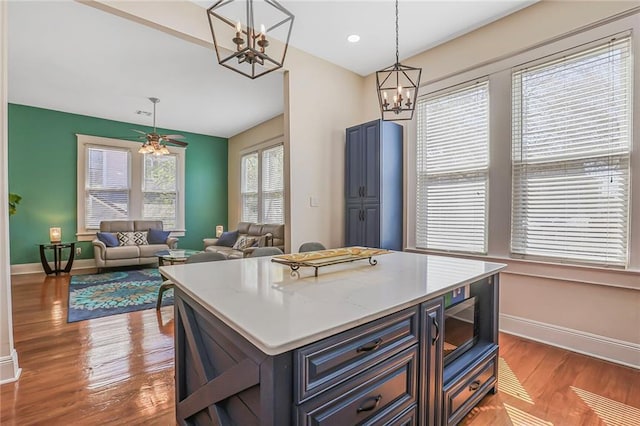 kitchen with pendant lighting, light countertops, baseboards, and wood finished floors