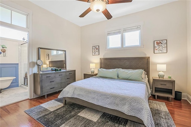 bedroom with a ceiling fan, wood finished floors, baseboards, and connected bathroom