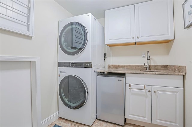 laundry area featuring laundry area, baseboards, stacked washer / drying machine, and a sink