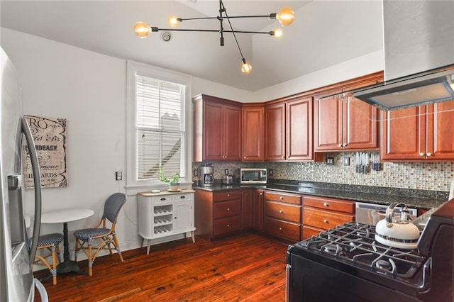 kitchen featuring tasteful backsplash, a chandelier, range hood, appliances with stainless steel finishes, and dark wood-style floors