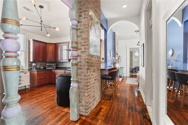 kitchen featuring dark countertops, visible vents, tasteful backsplash, and dark wood-style flooring