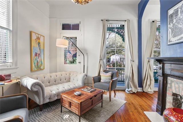 sitting room with a wealth of natural light, a multi sided fireplace, wood-type flooring, and baseboards