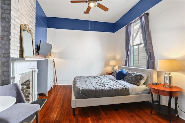 bedroom with baseboards, wood finished floors, and a fireplace