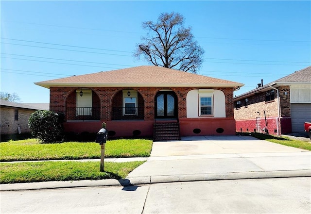 view of front of home featuring covered porch, a shingled roof, a front lawn, concrete driveway, and brick siding