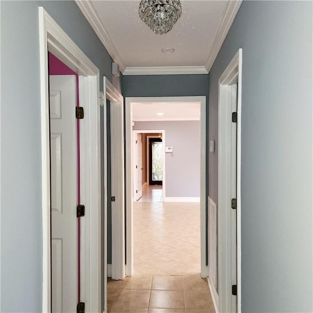 corridor featuring crown molding, light tile patterned floors, and baseboards