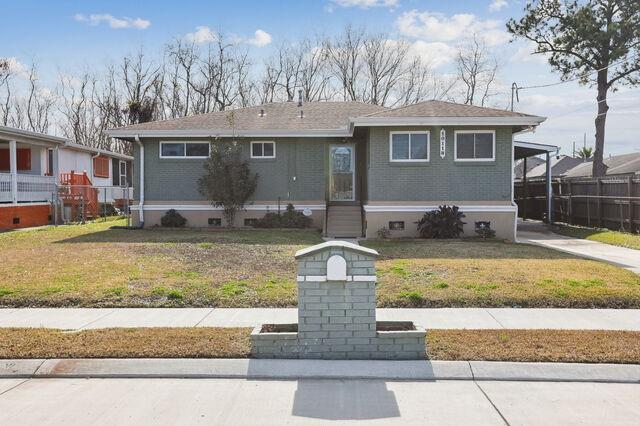 view of front of property featuring an attached carport, a front lawn, and brick siding