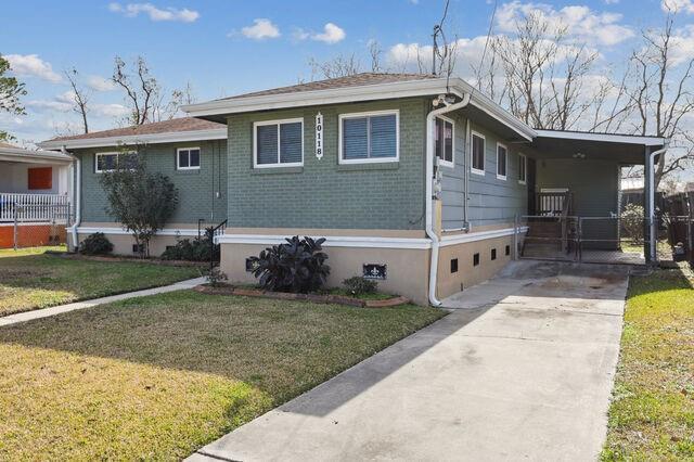 view of front of house featuring brick siding, concrete driveway, and a front yard