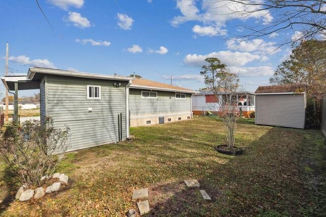 rear view of property with an outdoor structure, a storage unit, and a lawn