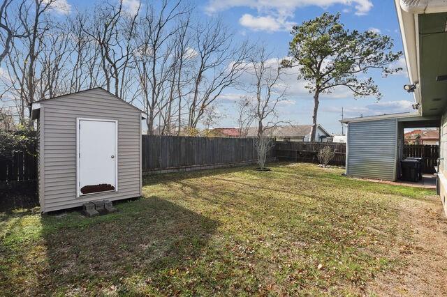 view of yard with an outdoor structure, a fenced backyard, and a shed