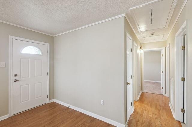 foyer featuring ornamental molding, baseboards, light wood-type flooring, and a textured ceiling