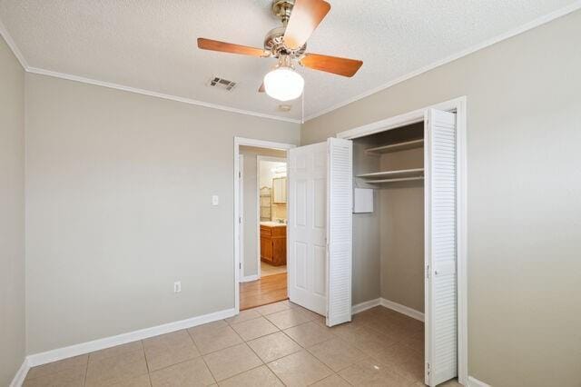 unfurnished bedroom with light tile patterned floors, visible vents, baseboards, and ornamental molding