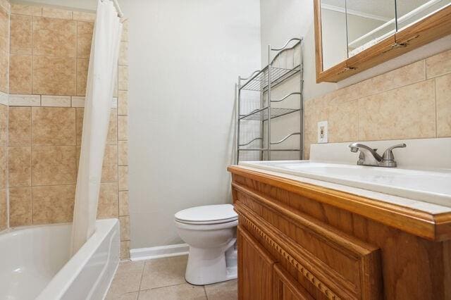 bathroom featuring vanity, baseboards, tile patterned flooring, shower / bath combo with shower curtain, and toilet