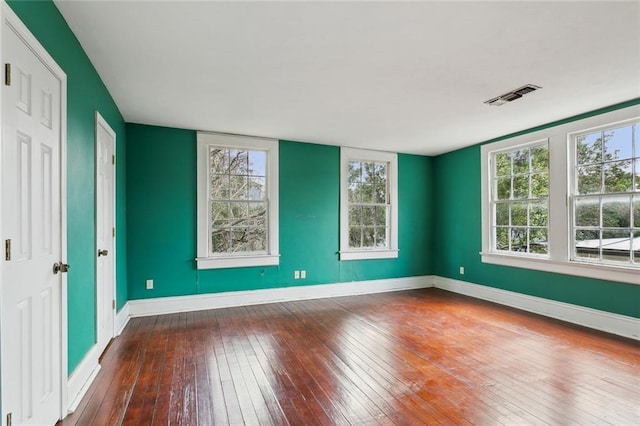 spare room with visible vents, wood-type flooring, and baseboards