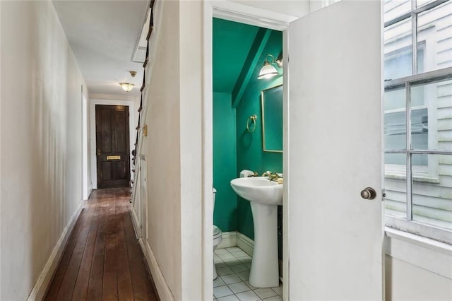 hallway with hardwood / wood-style floors, baseboards, and a sink