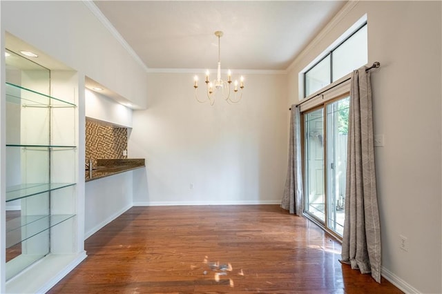 unfurnished dining area with baseboards, an inviting chandelier, wood finished floors, and ornamental molding