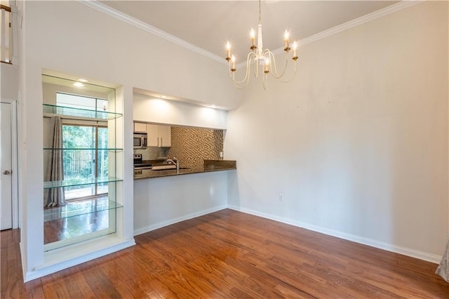 kitchen featuring dark wood finished floors, ornamental molding, stainless steel appliances, dark countertops, and backsplash