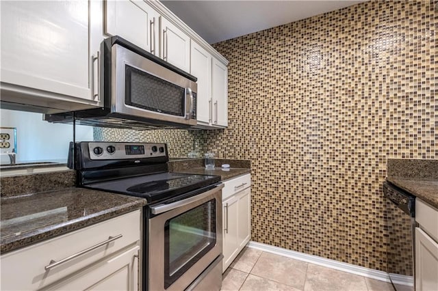 kitchen featuring tile walls, dark stone countertops, stainless steel appliances, light tile patterned flooring, and white cabinetry