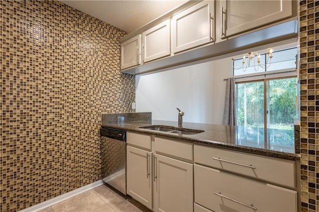 kitchen with a sink, dark stone countertops, stainless steel dishwasher, tile walls, and light tile patterned floors