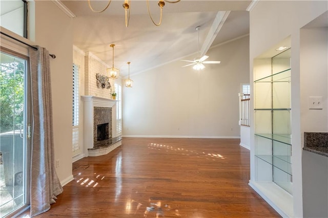 unfurnished living room featuring a fireplace with raised hearth, ornamental molding, ceiling fan with notable chandelier, wood finished floors, and baseboards