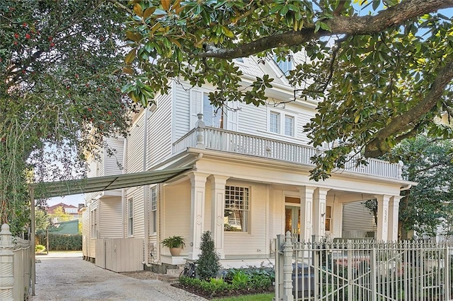 view of front of home featuring a balcony, fence, and covered porch