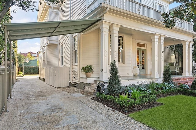 property entrance with covered porch, driveway, and a balcony