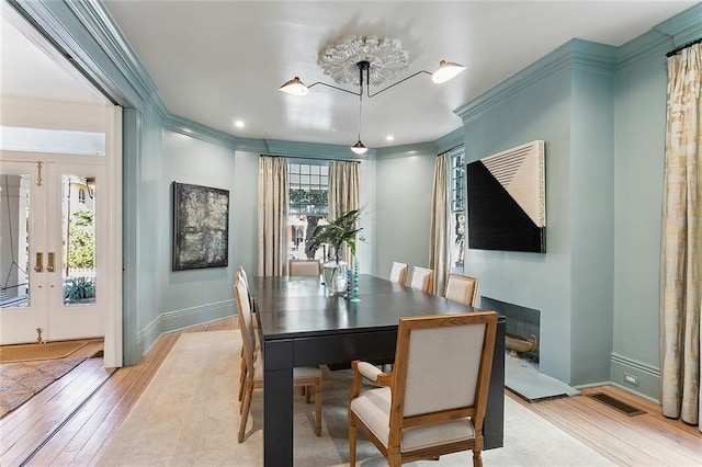 dining area with baseboards, light wood-style floors, and ornamental molding