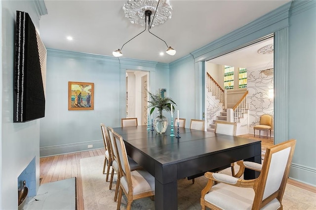 dining area featuring stairway, light wood-style flooring, baseboards, and ornamental molding