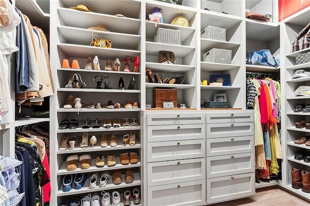 walk in closet with light wood finished floors