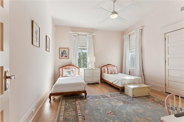 bedroom featuring visible vents, baseboards, a ceiling fan, and hardwood / wood-style flooring