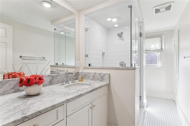 bathroom featuring vanity, visible vents, baseboards, a tile shower, and tile patterned flooring