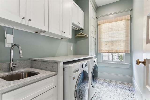 washroom featuring cabinet space, washing machine and dryer, baseboards, and a sink