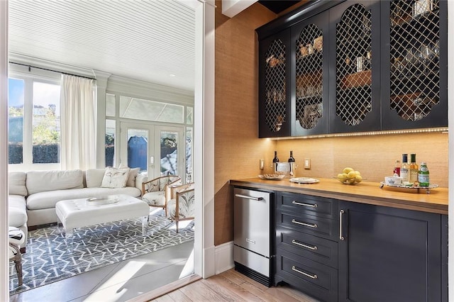 bar with a dry bar, french doors, light wood-style floors, and stainless steel dishwasher