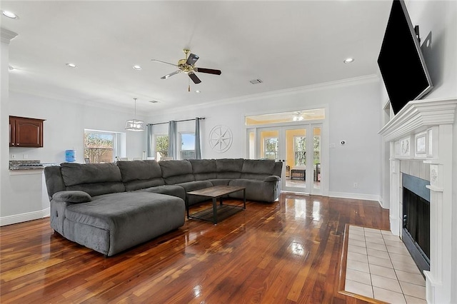 living room with visible vents, crown molding, baseboards, a fireplace with flush hearth, and wood-type flooring