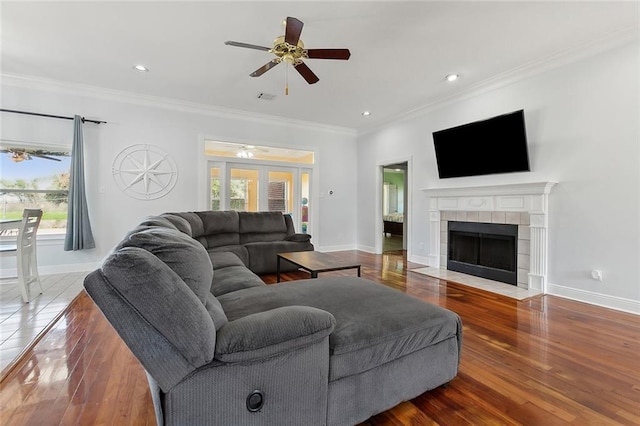 living room with a fireplace, crown molding, and wood finished floors