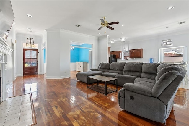 living area featuring recessed lighting, visible vents, ornamental molding, and wood finished floors