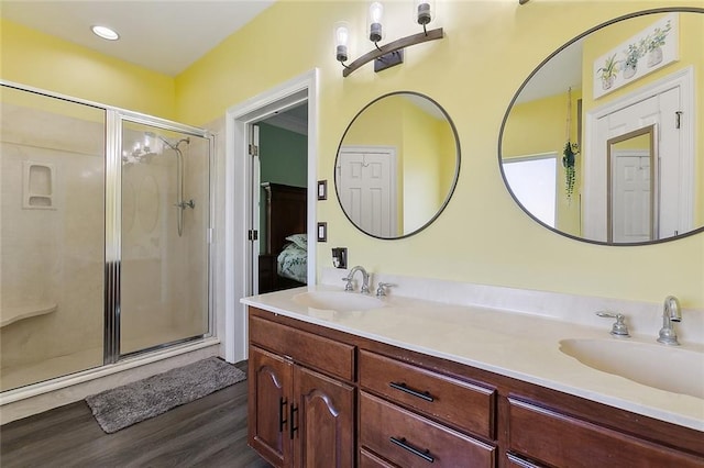 ensuite bathroom with double vanity, a stall shower, and a sink