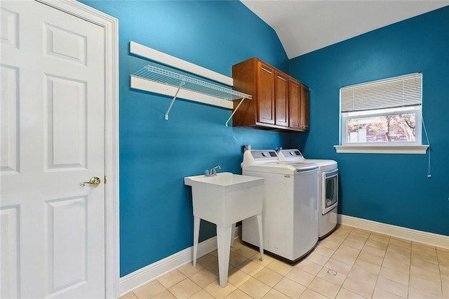 washroom featuring cabinet space, light tile patterned flooring, washing machine and dryer, and baseboards