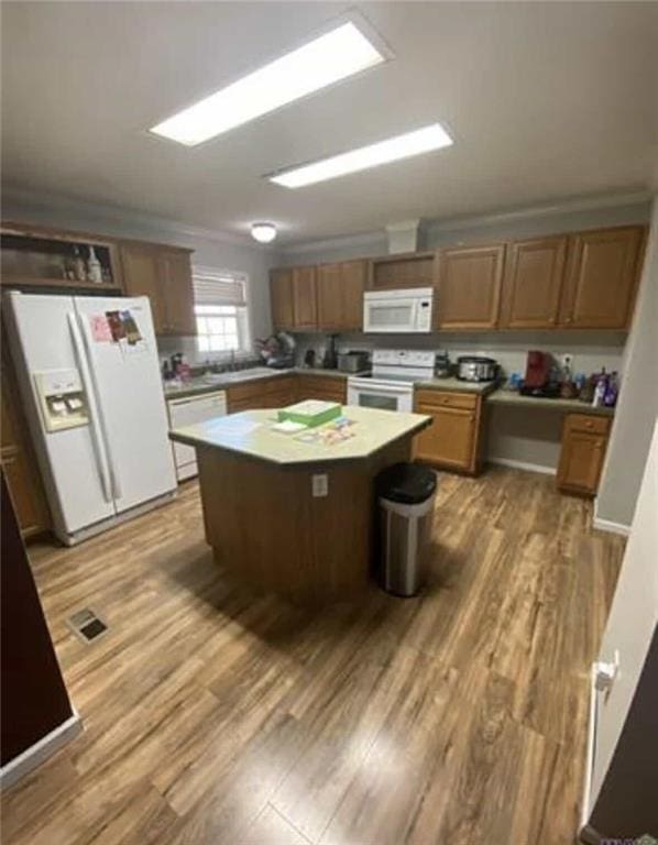 kitchen with light wood finished floors, white appliances, a kitchen island, and light countertops