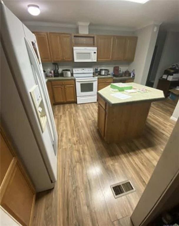 kitchen featuring visible vents, a center island, light countertops, light wood-style floors, and white appliances