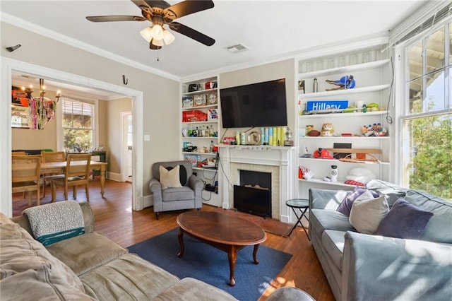 living room with visible vents, built in shelves, ceiling fan, ornamental molding, and wood finished floors