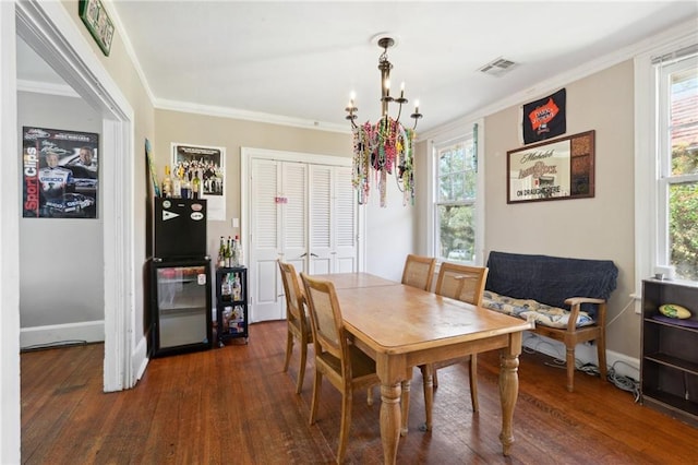 dining area with a chandelier, visible vents, crown molding, and wood finished floors