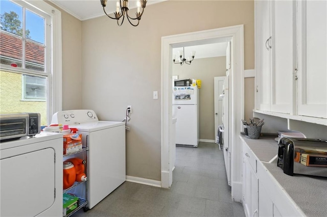 washroom featuring cabinet space, washing machine and dryer, baseboards, and an inviting chandelier