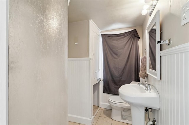 bathroom featuring tile patterned floors, toilet, and wainscoting