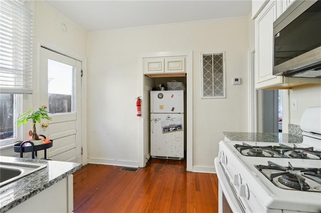 kitchen with dark wood finished floors, white appliances, white cabinets, and plenty of natural light